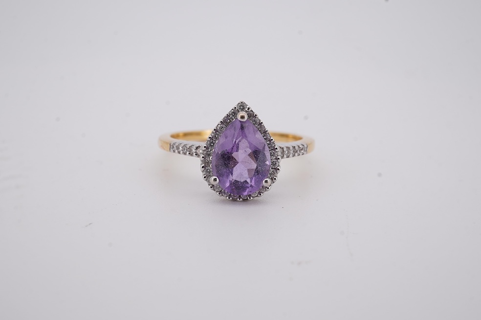 A modern 18ct gold and single stone pear cut amethyst set ring, with diamond chip set border and shoulders, size O, gross weight 3.4 grams. Condition - fair to good